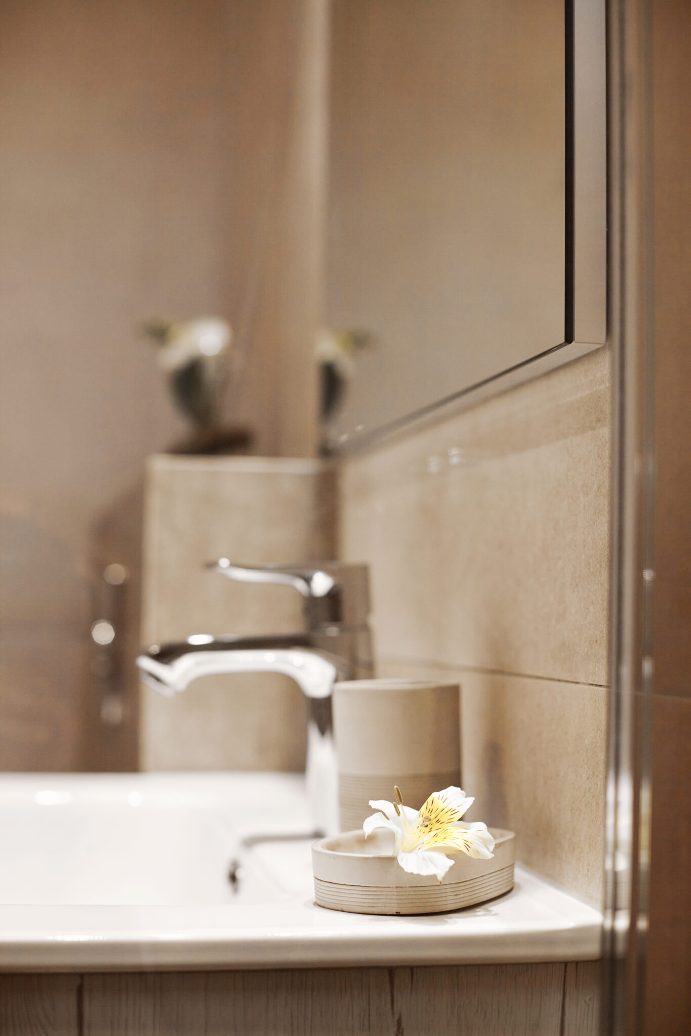 White ceramic washbasin, glossy metal faucet. Modern design of a light bathroom, close-up